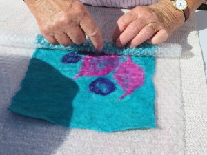 First she laid out the wool fibres in three layers - horizontal, vertical, horizontal and worked that together on a textured mat.  The fibres have to be dampened with warm water and a little detergent to get the fibres bonding together. 