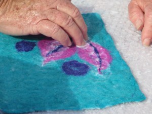 More fibres are added in a pattern and worked onto the existing felt.  The first bit can't be fully felted or the top layer won't take.